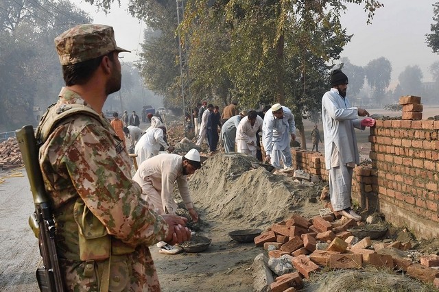 Pakistani labourers rebuild the wall of an army-run school