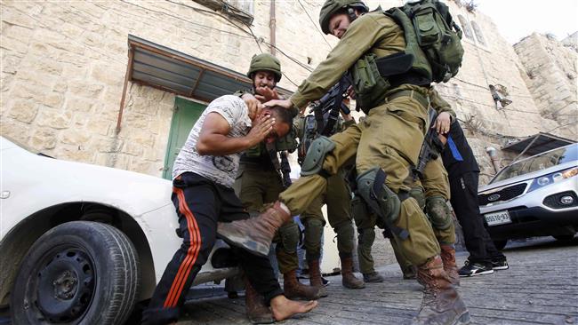An Israeli soldier kicks a Palestinian man as the regime forces try to arrest him in the West Bank city of al-Khalil, aka Hebron, on September 20, 2016. (Photo by AFP)
