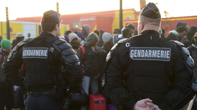 Gendarms stand guard as asylum seekers queue during the full evacuation of the “Jungle” refugee camp in Calais, northern France, on October 25, 2016. (Photo by AFP)