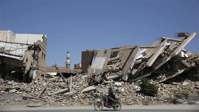 In this October 9, 2016 photo, a Yemeni man riding a motorcycle passes a building destroyed in a Saudi airstrike, in Sa’ada Province, northwest of Sana’a, Yemen. (By AP)
