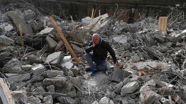 A Palestinian man sits amid the rubble of a house that was demolished by Israeli military bulldozers in the East Jerusalem al-Quds neighborhood of Beit Hanina on January 4, 2017. (Photo by AFP)
