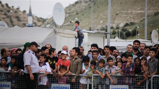 refugees trying to catch a glimpse of the German Chancellor visiting a refugee camp on the Turkish-Syrian border in Gaziantep, Turkey. (Photo by AFP)