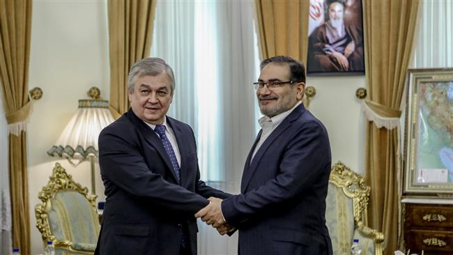 Secretary of Iran’s Supreme National Security Council Ali Shamkhani (R) shakes hands with Russia
