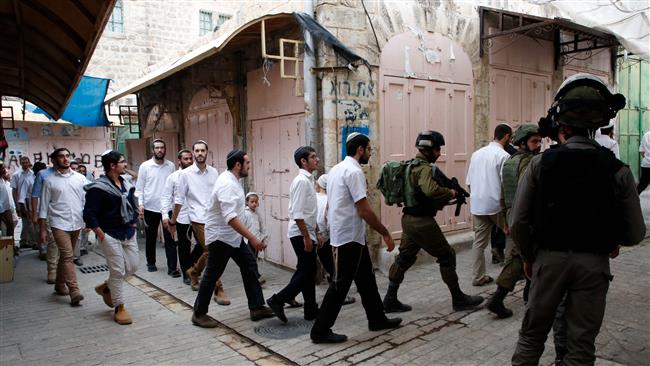 Israeli settlers and religious students are escorted by Israeli security forces during a tour of the Israeli-occupied West Bank city of al-Khalil (Hebron) on November 18, 2017. (Photo by AFP)
