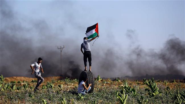 Palestinian protester waves the national flag during clashes with Israeli security forces near the border fence east of Jabalia refugee camp on June 23, 2017. (AFP photo)
