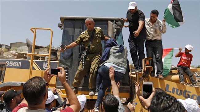 Demonstrators try to prevent a bulldozer from passing through in the Palestinian Bedouin village of Khan al-Ahmar, east of Jerusalem al-Quds in the occupied West Bank on July 4, 2018. (Photo by AFP)

