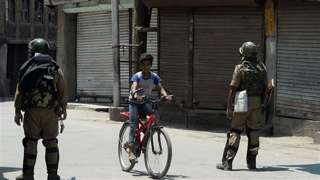 Indian paramilitary troopers stand guard in front of closed shops as a boy rides a bicycle in Srinagar, Kashmir, July 8, 2018. (Photo by AFP)
