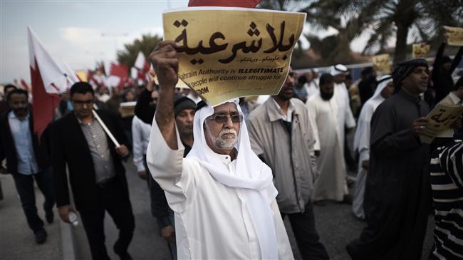 The photo, taken on December 26, 2014, shows a Bahraini man holding up an anti-regime placard during a protest in the village of Jannusan, west of the capital Manama. (Photo by AFP)
