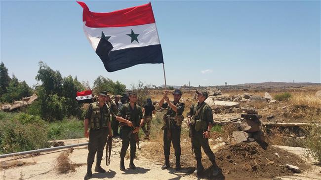 A handout picture released by the official Syrian Arab News Agency (SANA) on July 26, 2018 shows Syrian army soldiers carrying the national flag in the village of Hamidiya in the southern province of Quneitra.
