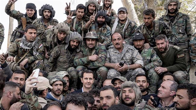 A file photo of Syrian President Bashar al-Assad (C) among a group of army soldiers
