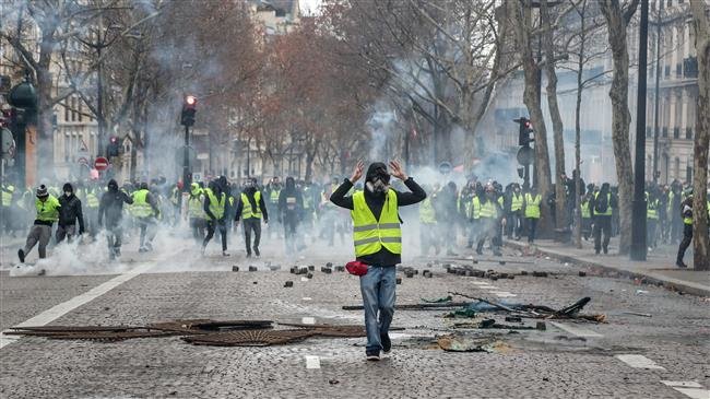 A protester wearing a yellow vest gestures during clashes with riot police and amid tear gas, near the Champs Elysees in Paris, France, on December 8, 2018. (Photo by AFP)
