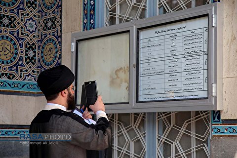 A clergyman in Qom uses his tablet to take picture of his class timetable