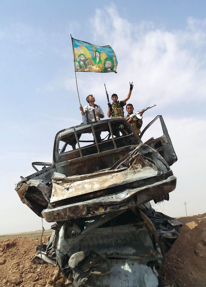 Iraqi Shia militia celebrate their destruction of Isis-owned vehicles outside Tikrit