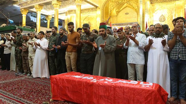 Iraqis pray over the coffin of an explosives expert and member of the Popular Mobilization units