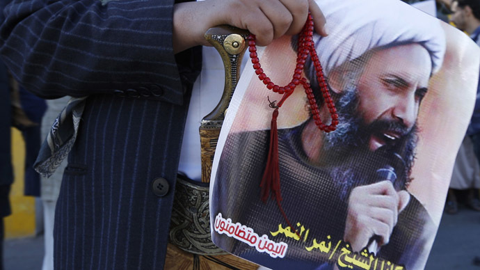 A Saudi anti-government protester carries a poster with the image of prominent Shia cleric Sheikh Nimr Baqir al-Nimr in the village of al-Awamiyah, Saudi Arabia.