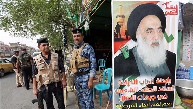 File photo shows Iraqi security forces standing next to a poster of Grand Ayatollah Ali Sistani in the capital Baghdad.