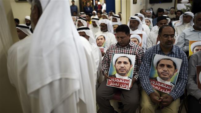 Bahraini men hold placards bearing the portrait of Sheikh Ali Salman, the head of al-Wefaq, during a protest against his detention, at al-Wefaq headquarters, on the outskirts of the capital, Manama, May ۲۹, ۲۰۱۶.