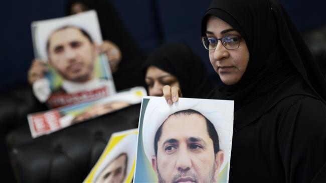 Bahraini women hold placards bearing the portrait of Sheikh Ali Salman, the imprisoned secretary general of al-Wefaq during a protest on the outskirts of the capital, Manama, September ۱۴, ۲۰۱۵