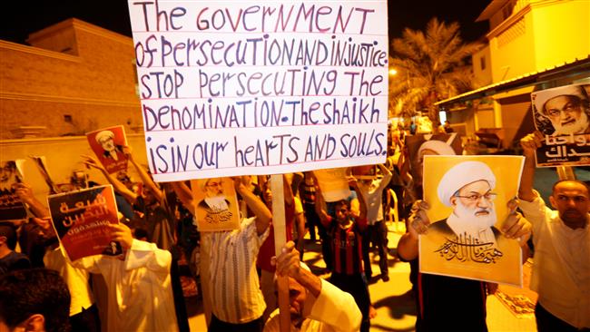 People hold banners and posters is support of Bahrain’s top Shi’a cleric, Ayatollah Isa Qasim, during a sit-in outside his home in the village of Diraz on July 27, 2016.