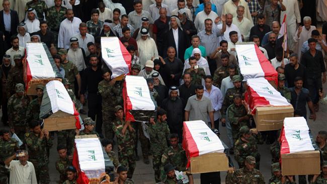 Iraqi soldiers carry coffins containing the remains of ten of their comrades who were killed in the Speicher massacre