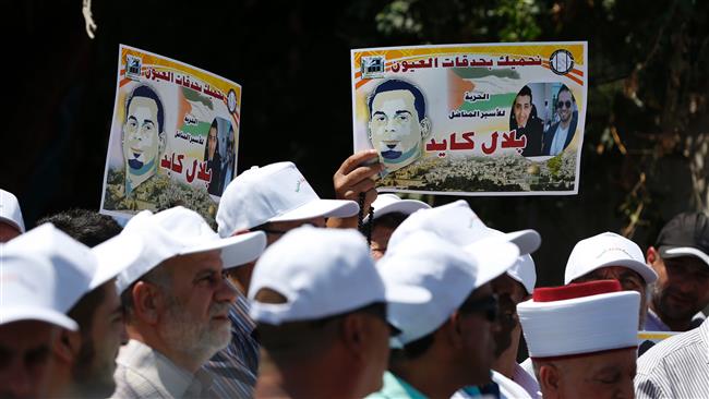 Palestinian protesters hold posters against the so-called administrative detention of Palestinian prisoner Bilal Kayed outside the International Committee of the Red Cross’s offices in East Jerusalem al-Quds