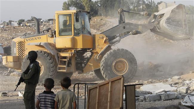 An Israeli bulldozer destroys Palestinian homes and a community center in the southern West Bank village of Umm al-Kheir