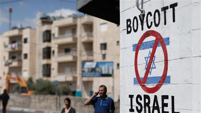 Palestinians walking past a sign painted on a wall in the West Bank