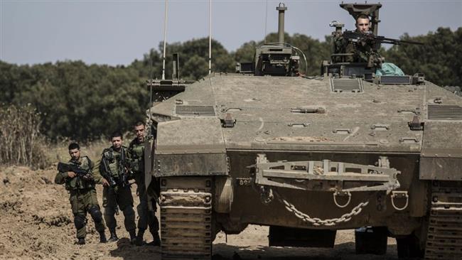 Israeli soldiers stand by a tank near the Gaza Strip