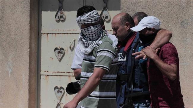 Palestinian photojournalist Nidal Shtayyah (C) is helped by Palestinian protesters during skirmishes with Israeli military forces in the occupied West Bank town of Kafr Qaddum, September 2, 2016.