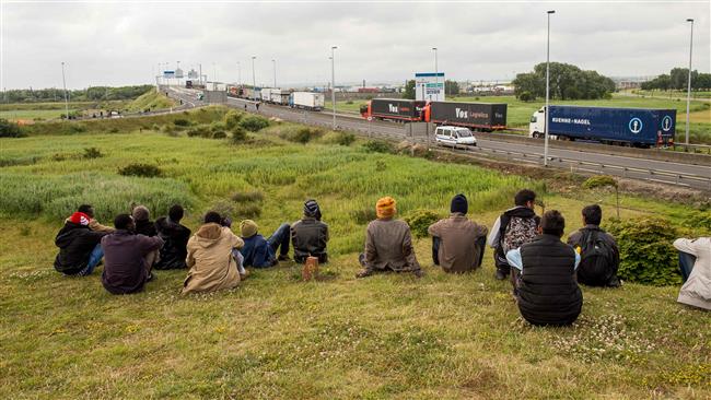 This file photo shows refugees sitting near the A16 highway as they try to access the Channel Tunnel in Calais, northern France. (AFP)
