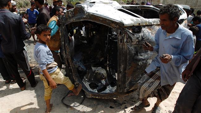 Yemeni onlookers inspect a charred vehicle on September 9, 2016, after two improvised explosive devices (IEDs) went off inside a car in the capital Sana