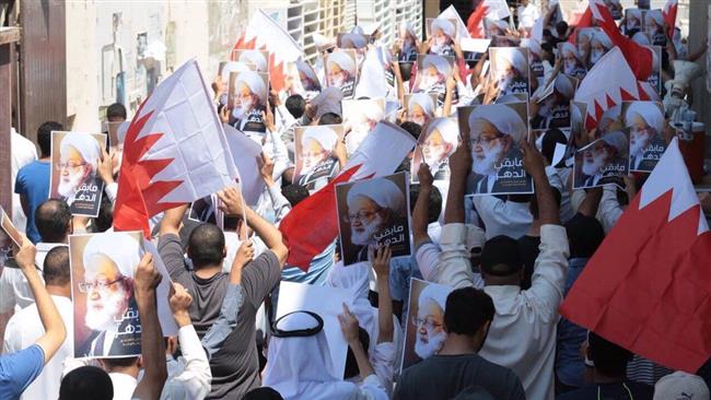 Protesters hold Bahraini flags and placards with the images of Bahrain