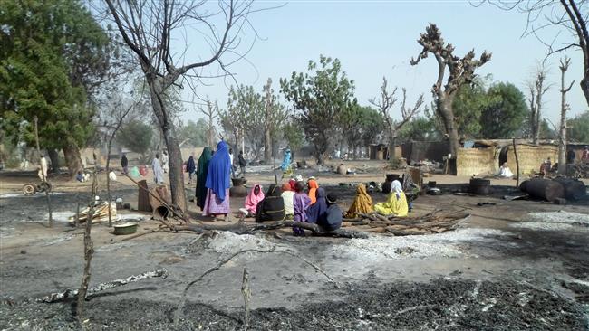 Women and children sit among burnt houses after Boko Haram militants attack a village on the outskirts of Maiduguri in northeastern Nigeria on January 31, 2016. (Photo by AFP)
