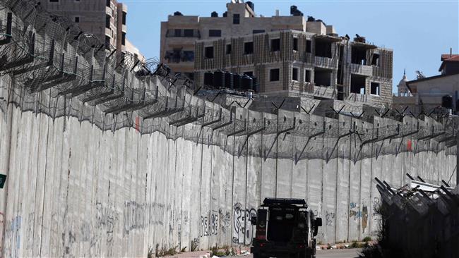 An Israeli police car patrols along a section of a wall separating the West Bank city of al-Ram (L) from Jerusalem al-Quds on February 24, 2016. (Photo by AFP)