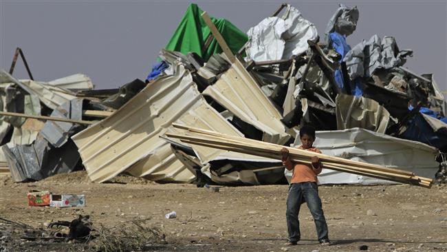 A Bedouin boy carries timber after Israeli forces removed temporary shacks from the site earlier, in al-Araqeeb village in the Negev region of the occupied Palestinian territories. (Photo by AP)