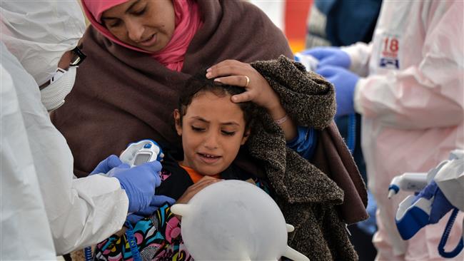 A woman and child look on as members of the Italian Red Cross examine them after they disembarked from the Topaz Responder, a rescue ship run by the Maltese NGO MOAS, at Brindisi
