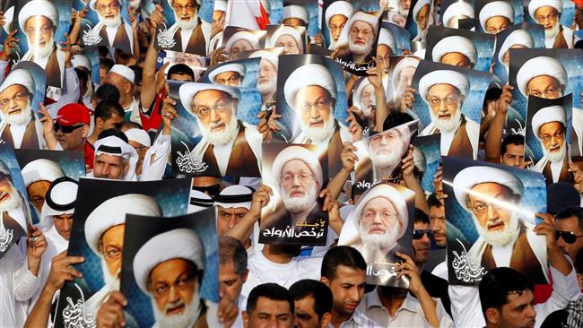 Bahraini anti-regime protesters carrying posters of senior Shia cleric Sheikh Issa Qassim. 