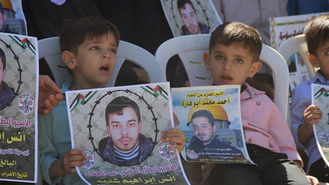 In this file photo, Palestinian children hold the portraits of Palestinian hunger strikers Anas Ibrahim Shadid (L) and Ahmad Abu Farah during a protest in the occupied West Bank.
