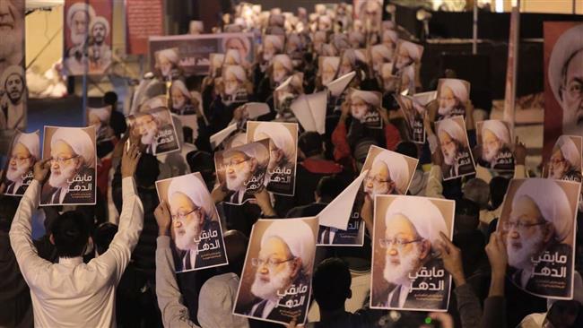 Bahraini demonstrators attend a protest against the revocation of the citizenship of the top Bahraini Shia cleric, Sheikh Isa Qassim (portrait), near his house in the village of Diraz, west of Manama on December 15, 2016.
