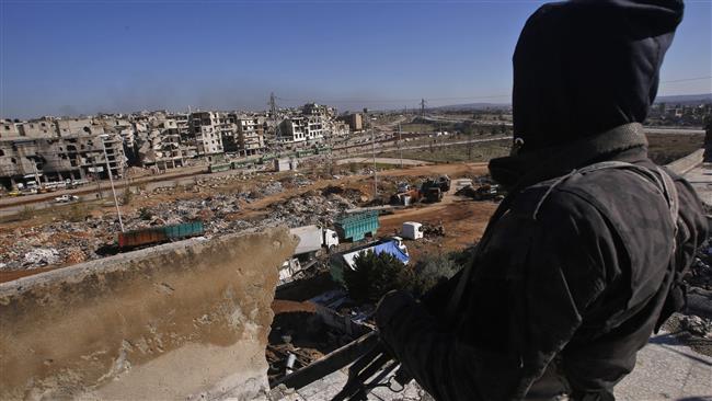 A member of the Syrian pro-government forces watches buses in the distance during an evacuation operation of militants and their families from the eastern neighborhoods of Aleppo on December 15, 2016.
