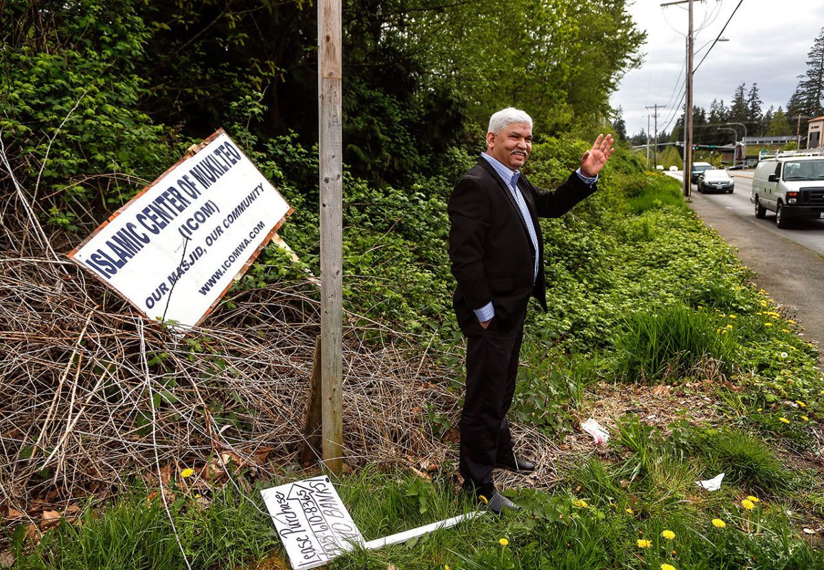 Mohammed Riaz Khan waves at a passerby he knows near the intersection of Harbour Point Blvd. and Mukilteo Speedway, while visiting the site of the planned mosque, The Islamic Center of Mukilteo, in early May. The signage, which had fallen or was blown down, is at the east end of the property.