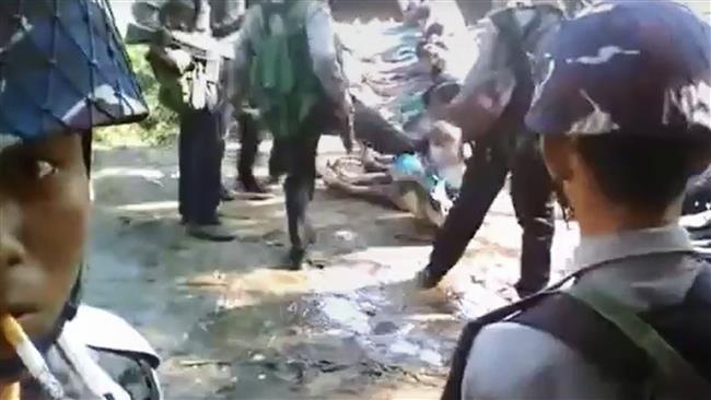 This screen grab, taken on January 4, 2017 from a YouTube video, shows a policeman (back-C) kicking a Rohingya minority villager seated on the ground with others, in the village of Kotankauk, November 5, 2016. (Via AFP)
