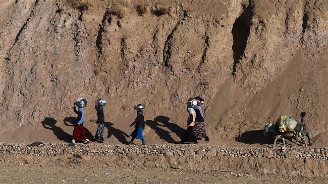 A group of Afghan Shia Muslims walking along a mountain path in Bamiyan province.