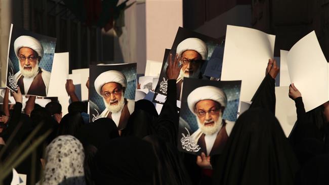 The file photo shows Bahraini protesters carrying pictures of top Shia cleric Sheikh Issa Qassim during an anti-regime rally in Diraz.