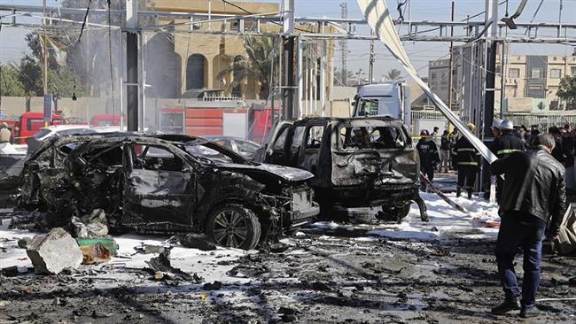 Iraqi security forces and citizens inspect the scene after a car bomb attack at a car garage in the capital, Baghdad, on January 24, 2017