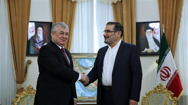 Secretary of Iran’s Supreme National Security Council Ali Shamkhani (R) shakes hands with Russia