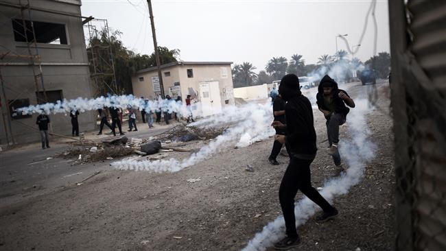 The photo taken on February 13, 2015 shows Bahraini protesters taking cover from tear gas during clashes with police following a demonstration on February 13, 2015, to mark the fourth anniversary of the Bahraini uprising, in the village of Bilad al-Qadim on the outskirts of the capital, Manama. (Photo by AFP)
