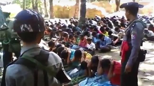 This screen grab taken on January 4, 2017 from a YouTube video shows policemen standing guard around Rohingya minority villagers seated on the ground in the village of Kotankauk during a police area clearance operation on November 5, 2016. (Photo by AFP)
