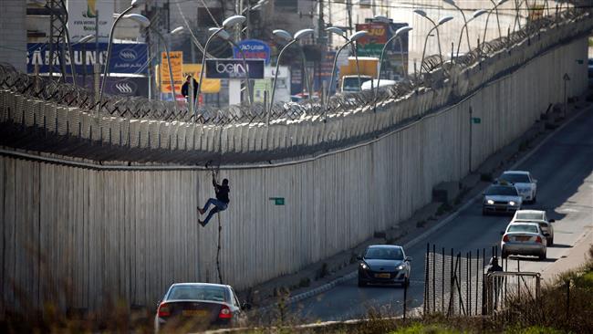 A Palestinian man climbs over a section of Israel