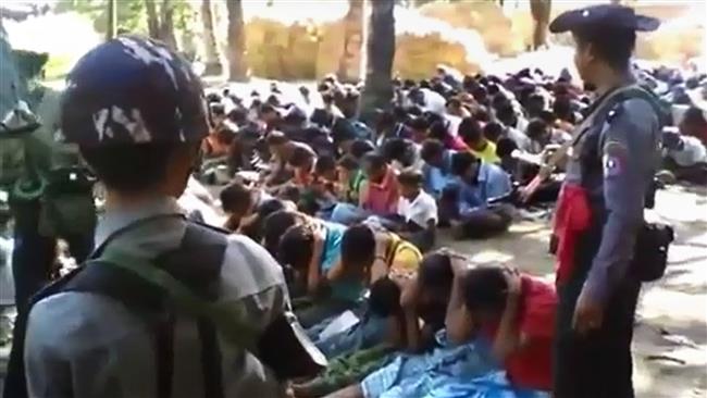 This screen grab taken on January 4, 2017, from a YouTube video originally taken by Myanmar Constable Zaw Myo Htike (not pictured) shows policemen standing guard around Rohingya minority villagers seated on the ground in the village of Kotankauk during a police area clearance operation on November 5, 2016. (Photo by AFP)
